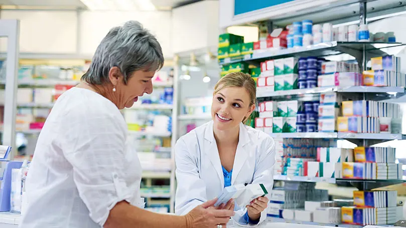 Apothekerin zeigt Patientin zwei Packungen