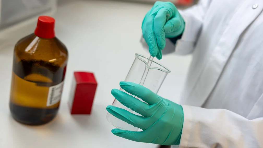 PTA stellt Lösung im Becherglas her; zwei Substanzen stehen auf dem Labortisch daneben