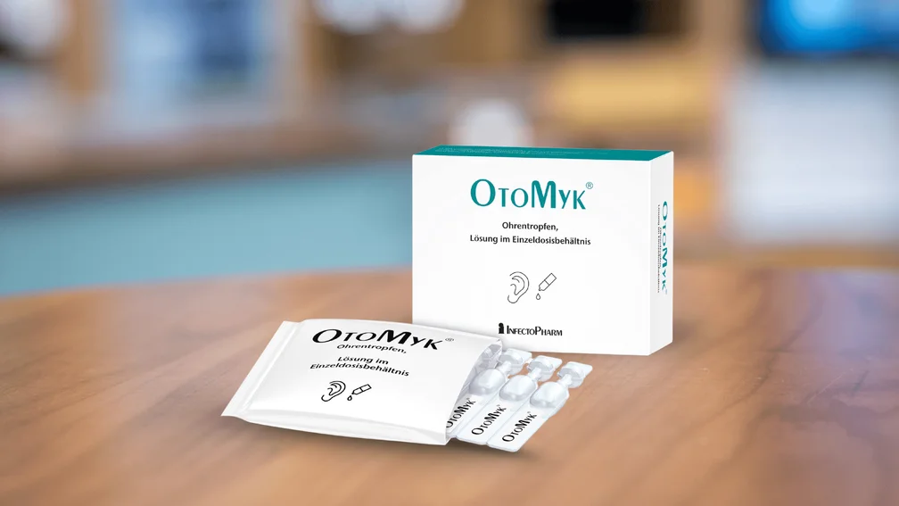 Verpackung OtoMyk Ohrentropfen liegen auf HV-Tisch