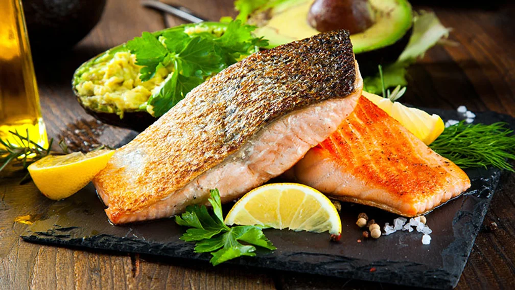 zwei Portionen gegrillter Lachs auf einer schwarzen Schieferplatte
