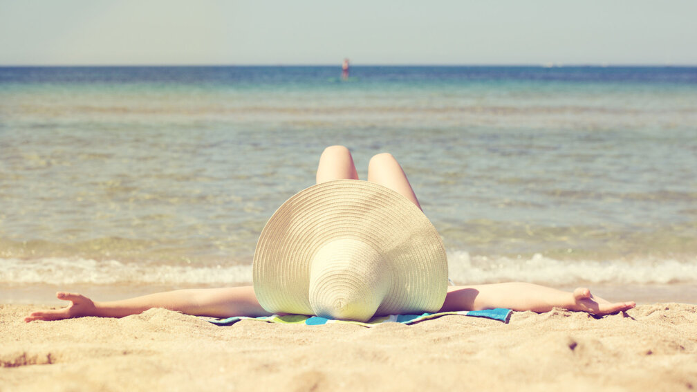 junge Frau liegt am Strand und bräunt sich