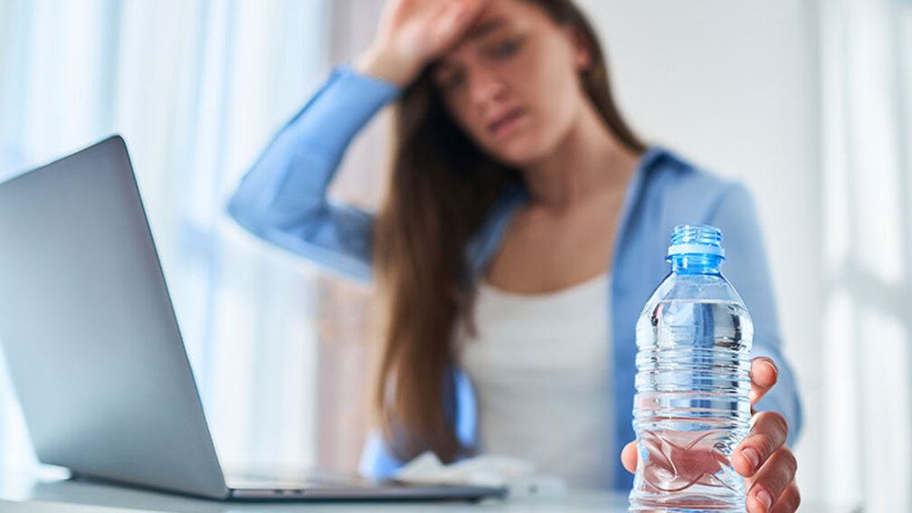 Wegen Hitze erschöpfte Berufstätige greift zur Wasserflasche