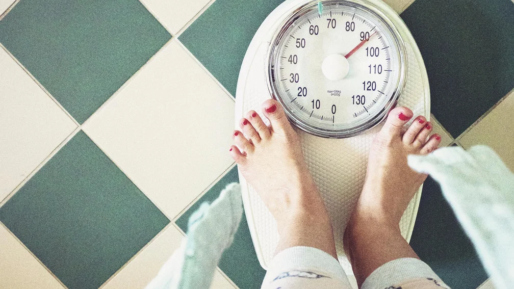 Füße auf einer Körperwaage, welche über 90kg anzeigt.