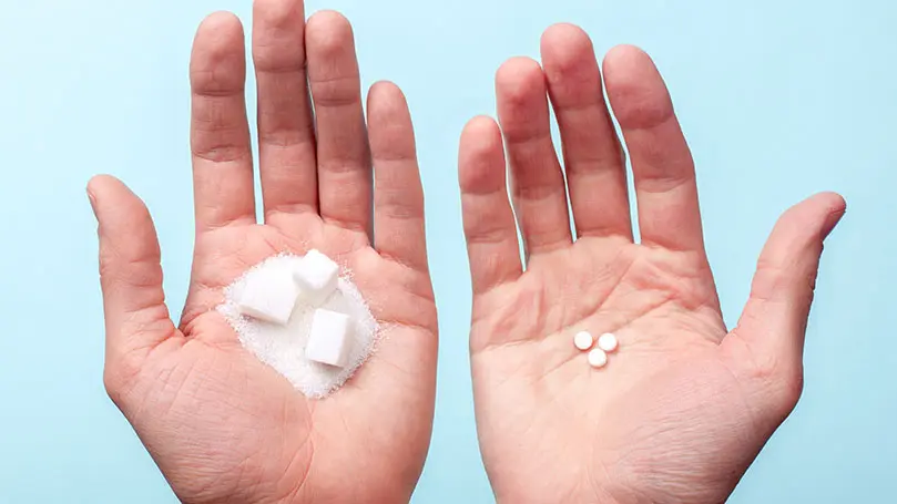 in den Handflächen von zwei Männerhänden liegen Zuckerwürfel und Süßstofftabletten