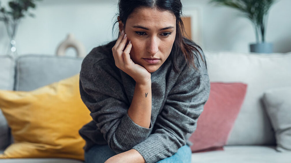 Depressive Frau sitzt auf Sofa