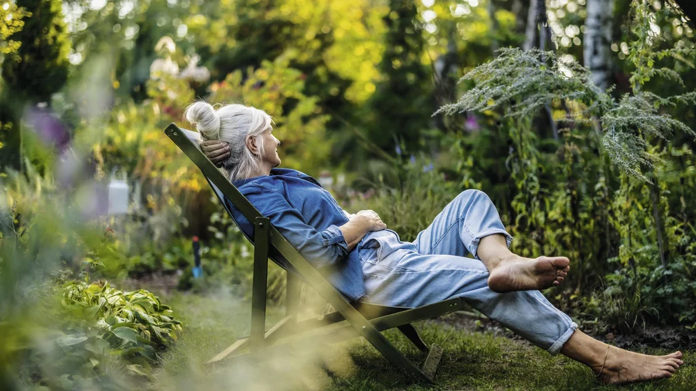 Frau liegt auf Liegestuhl im Garten