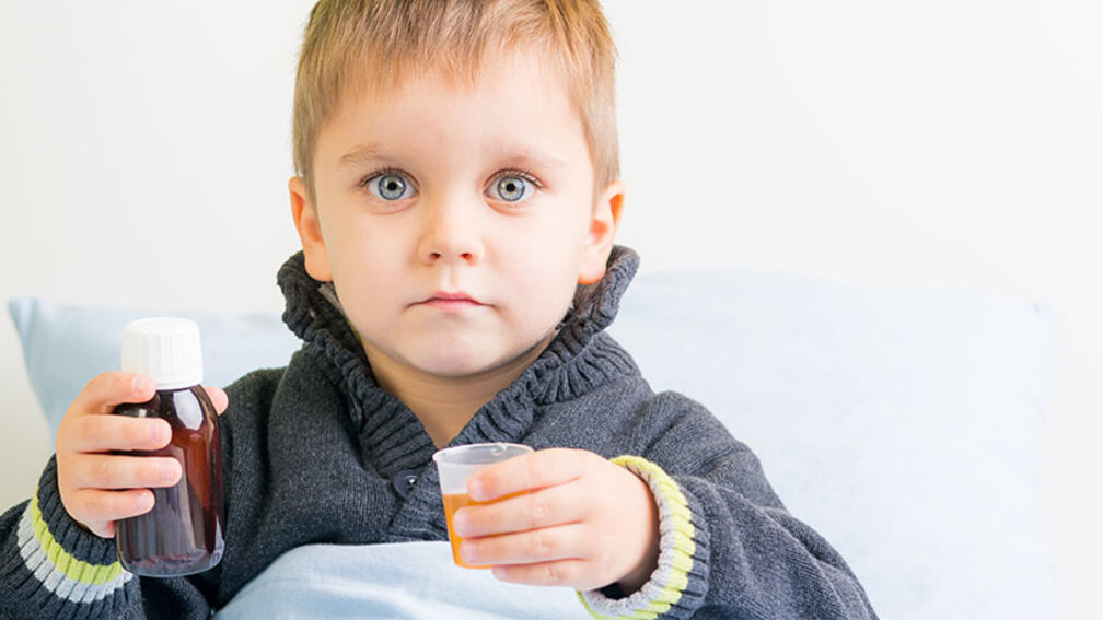 Kleiner Junge hält Antibiotikasaft in der Hand
