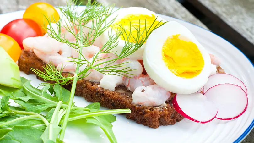 Roggenbrot mit Krabben und Eischeiben auf weißem Porzellanteller