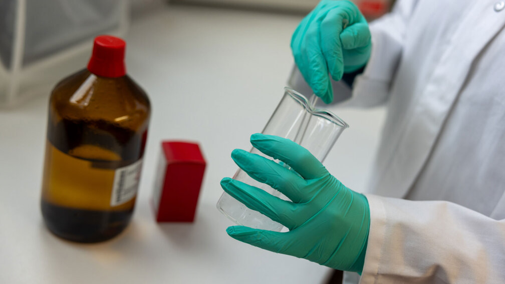 PTA rührt mit einem Glasstab eine Flüssigkeit im Becherglas