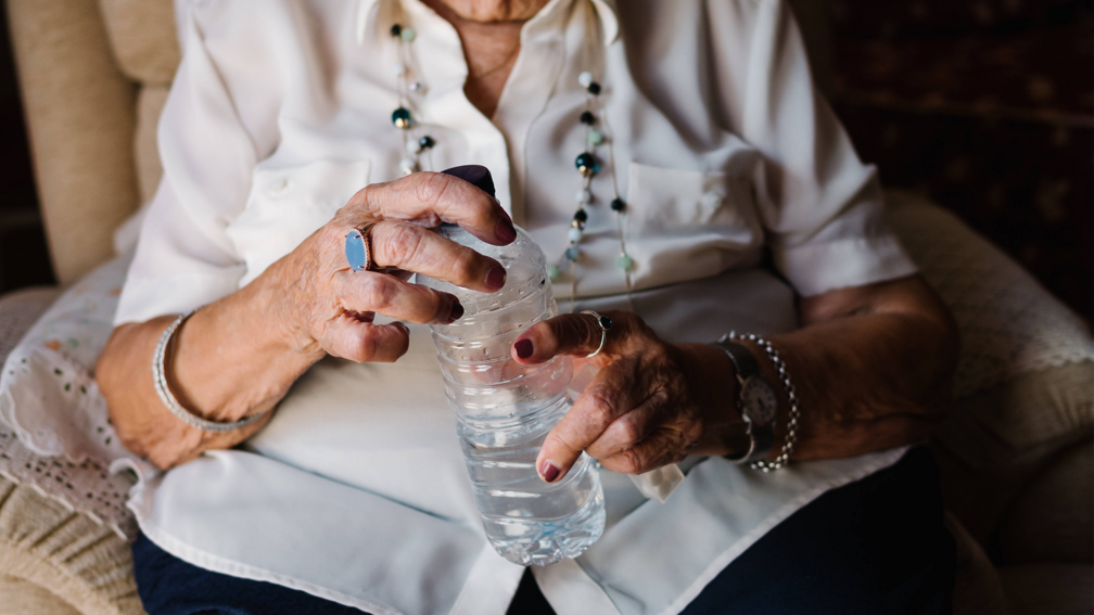 Seniorin hält Wasserflasche in den Händen