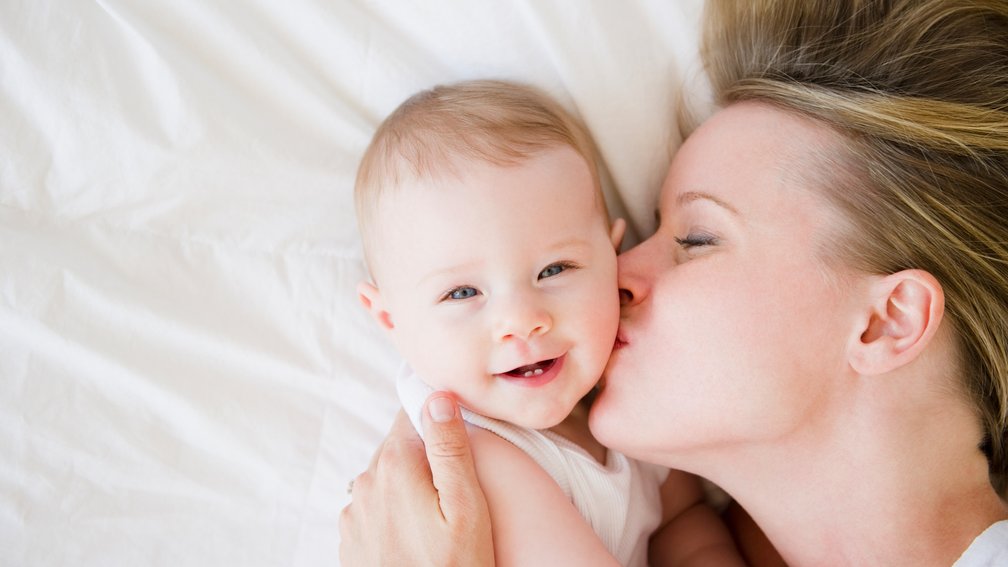 Mama küsst die Backe ihres Babys