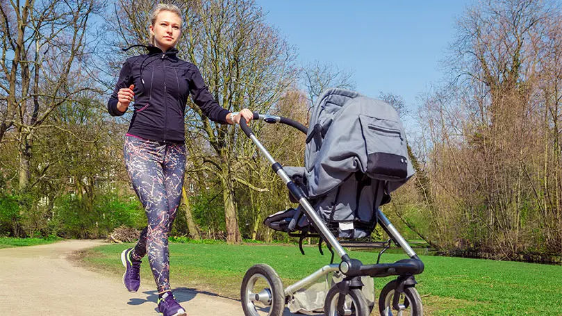 Joggende Mutter im Park mit Kinderwagen