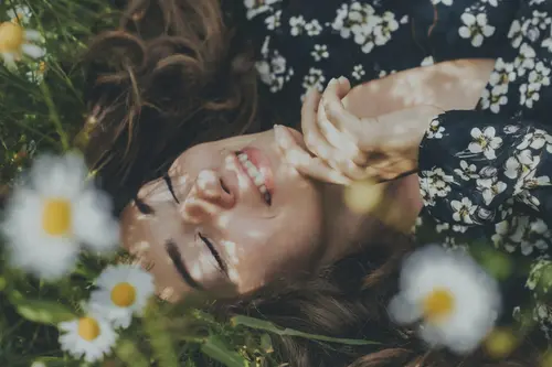 Eine Frau liegt in einer Blumenwiese