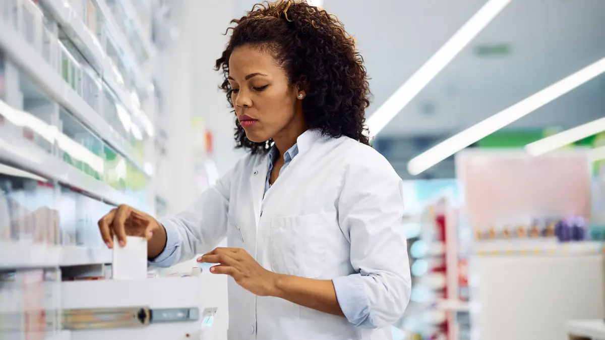 PTa steht vor einer aufgezogenen Schublade und sucht ein Arzneimittel