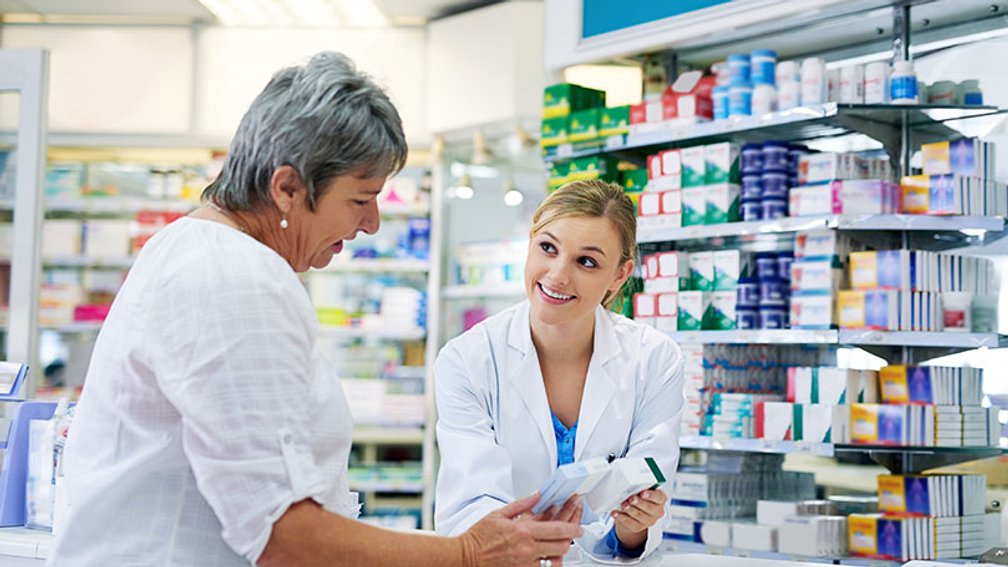 Apothekerin zeigt Patientin zwei Packungen