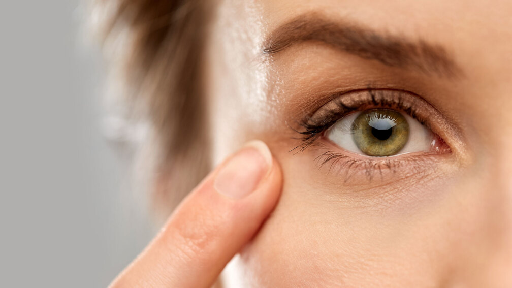 Frau fasst sich mit dem Zeigefinger ans Auge