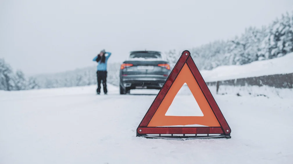 Warndreieck vorne, dahinter Person mit einer Autopanne