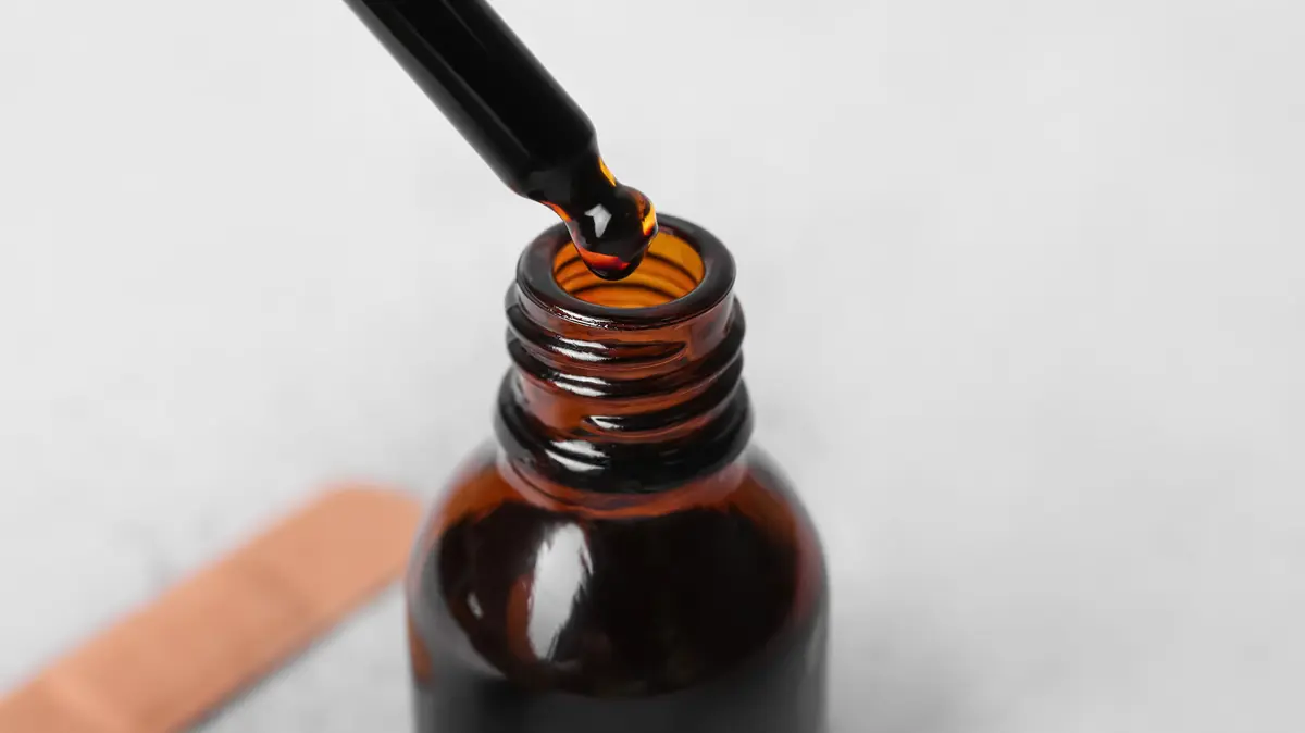 Braunglasflasche mit Pipette, darin ist eine braune Lösung enthalten