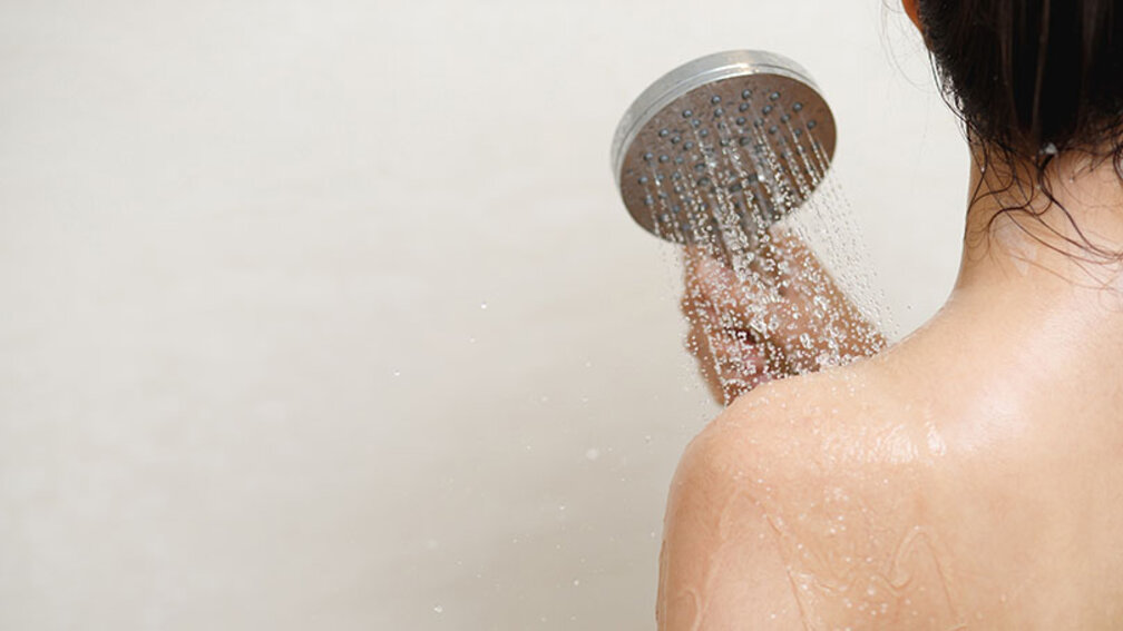 Frau steht unter Dusche