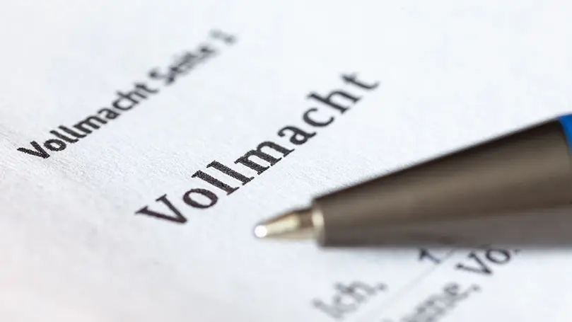 Weißes Blatt mit Fokus auf Schriftzug Vollmacht, davor unscharf ein Kugelschreiber