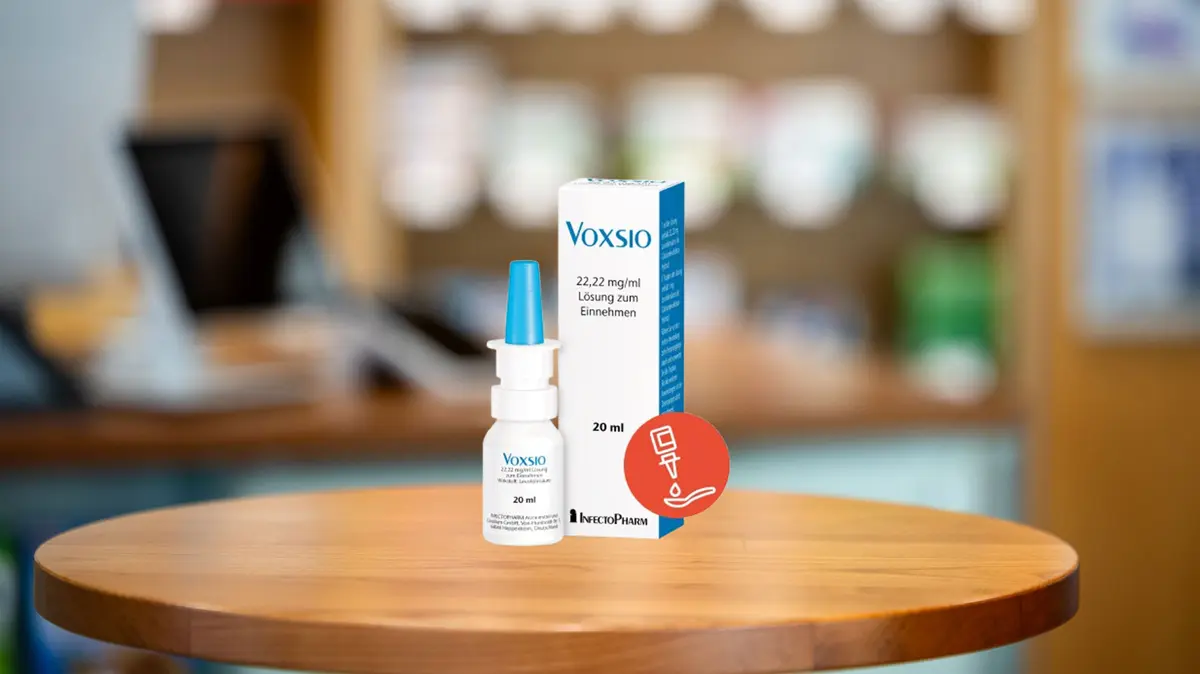 Dosierspray und Verpackung von Voxsio Tropfen stehen nebeneinander auf dem HV-Tisch