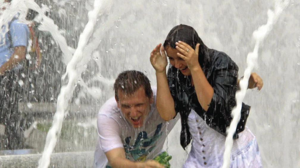 Zwei Menschen stehen nass in einem Springbrunnen