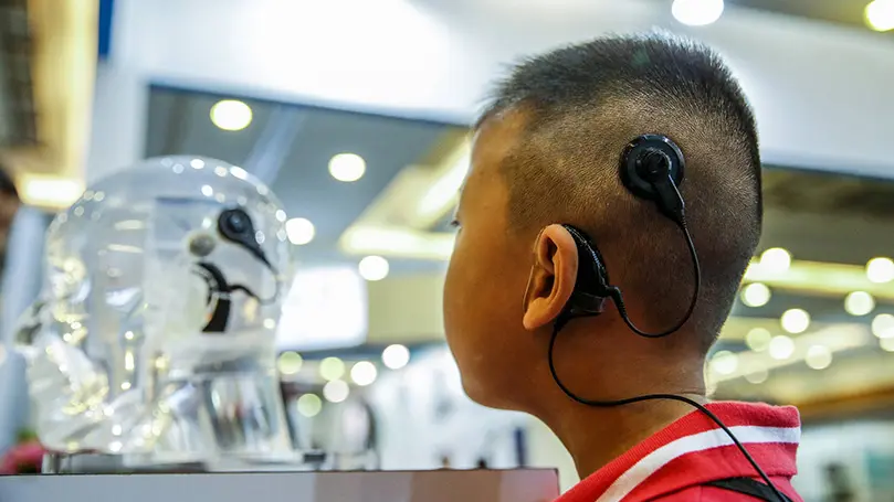 Asiatischer Junge mit Cochlea-Implantat am linken Ohr