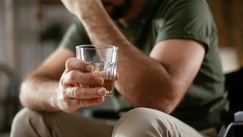 Mann hält Glas mit Alkohol in der Hand