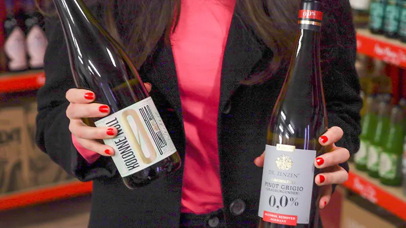 Frau hält zwei Flaschen alkoholfreien Wein in die Kamera