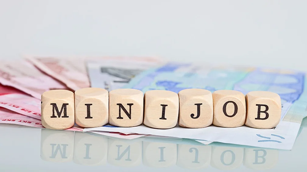 Würfel auf Geldscheinen bilden das Wort Minijob