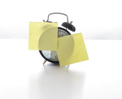 An einem Wecker kleben zwei gelbe Post-its.