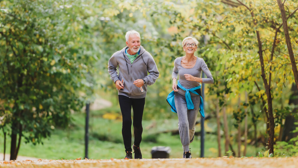 Mann und Frau im Rentenalter joggen im Wald