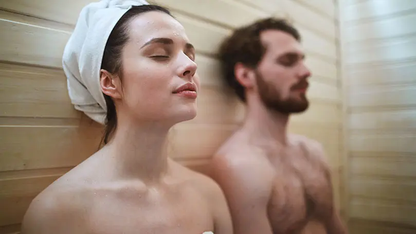 Mann und Frau sitzen mit geschlossenen Augen in der Sauna