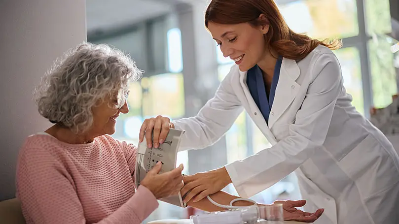 Apothekerin legt Patienten Manschette zur Blutdruckmessung an