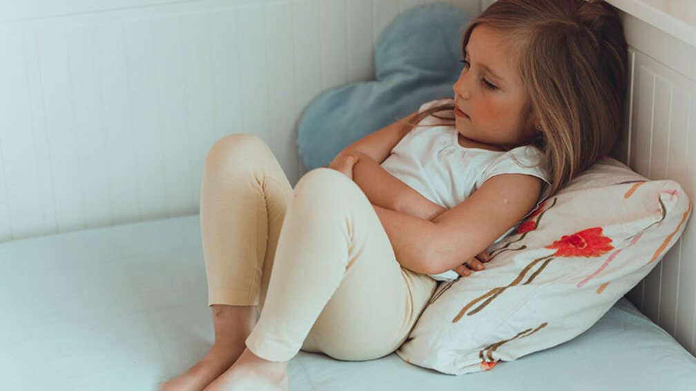 Mädchen mit Bauchschmerzen im Bett