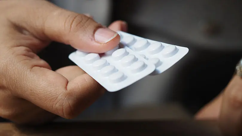 Eine Hand hält zwei weiße Blister mit runden Tabletten