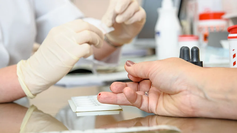 Im Fokus ein Ringfinger mit blutender Einstichstelle