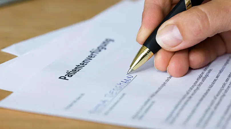 Ausfüllen einer Patientenverfügung mit Kugelschreiber
