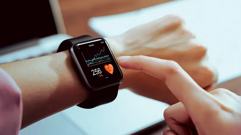 Eine Smart-Watch wird am linken Handgelenk zentriert dargestellt und bedient, auf der Uhr ist eine Kalorienanzeige mit weiteren Graphen zu sehen