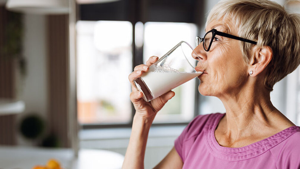 Profil-Aufnahme einer Frau, die Milch aus einem Glas trinkt