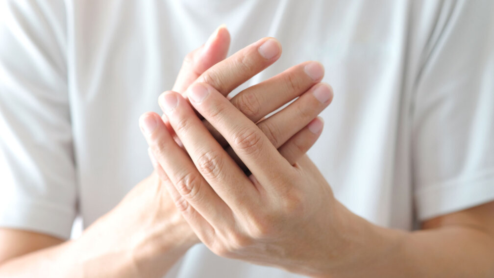 Mann hält eigene Hand mit der anderen Hand fest