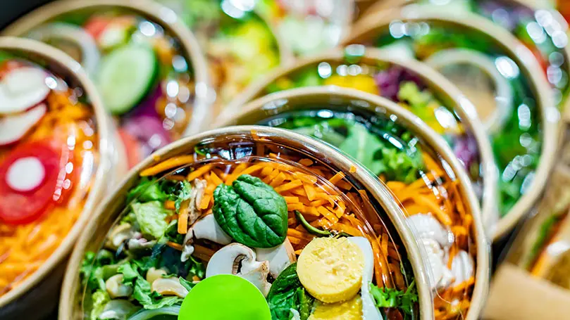 mehrere abgepackte Salate in einem Kühlregal