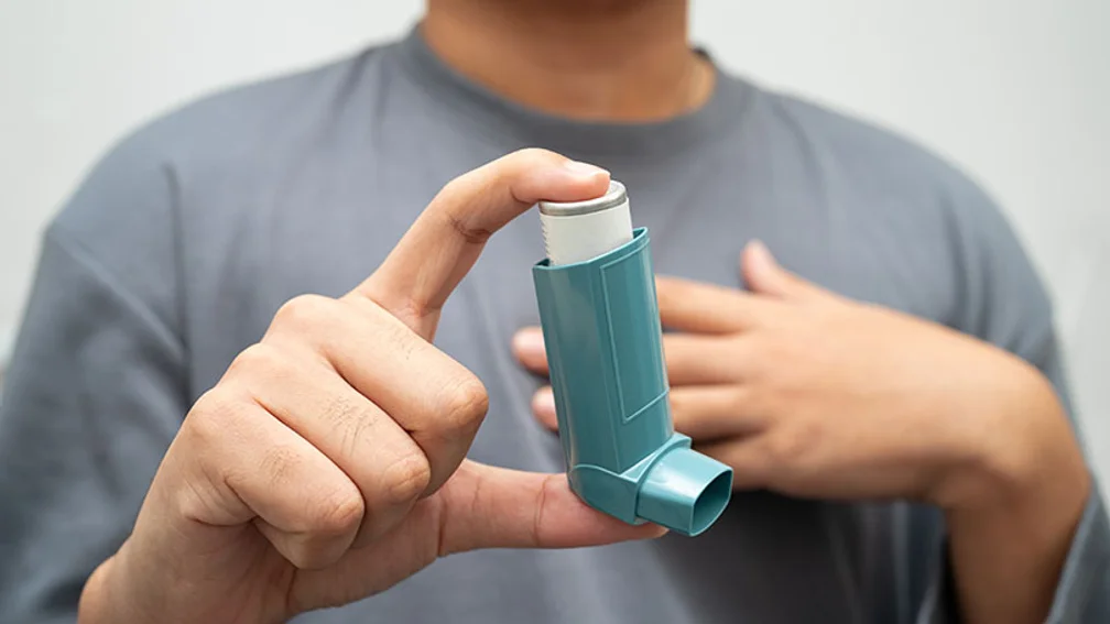 Mann hält zwischen Daumen und Zeigefinger ein Dosieraerosol