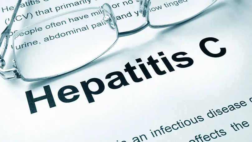 Hepatitis C als Überschrift auf Papier mit Brille auf Tisch liegend