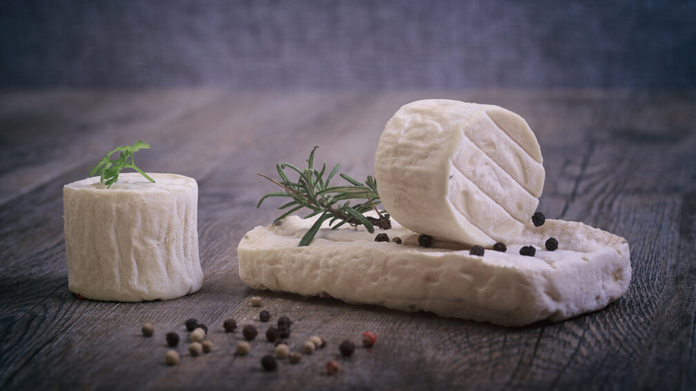 Drei Stück Rohmilchkäse auf Holzuntergrund