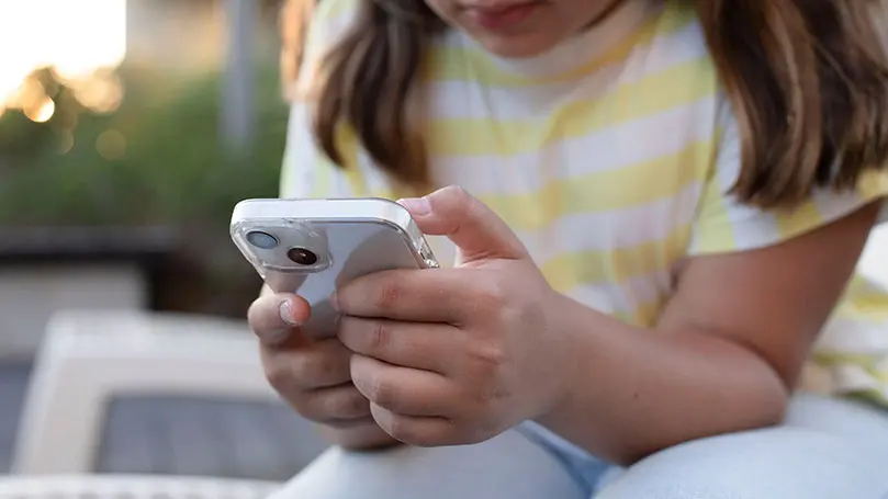 Smartphone in den Händen eines dunkelhaarigen Mädchens