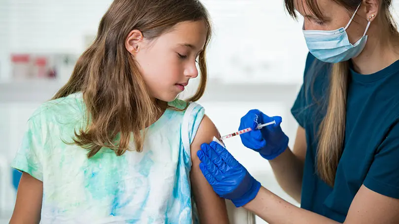 Teenager beobachtet Ärztin, die ihr eine Impfspritze in den linken Oberarm sticht