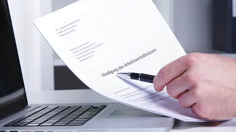 Mann zeigt mit Kugelschreiber auf Brief mit Kündigung des Arbeitsverhältnisses
