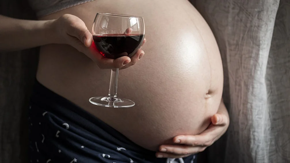Schwangere hält Glas mit Rotwein in der Hand