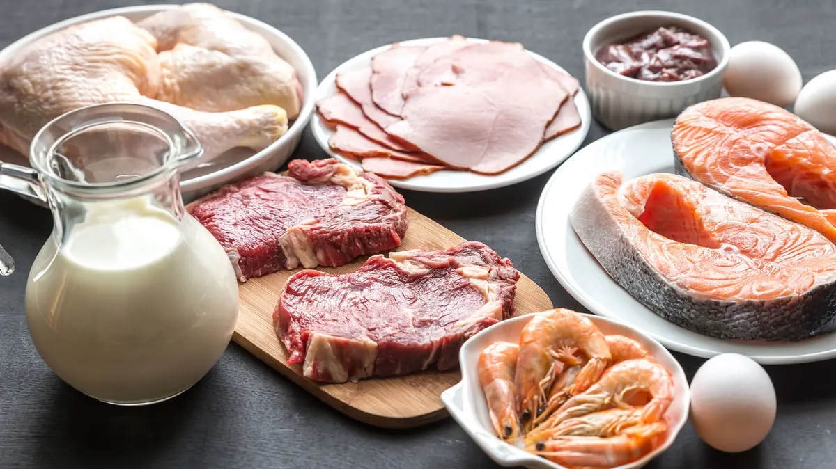 verschiedene Lebensmittel liegen auf dem Tisch, darunter eine Kanne mit Milch, Fleisch, Eier und Meeresfrüchte